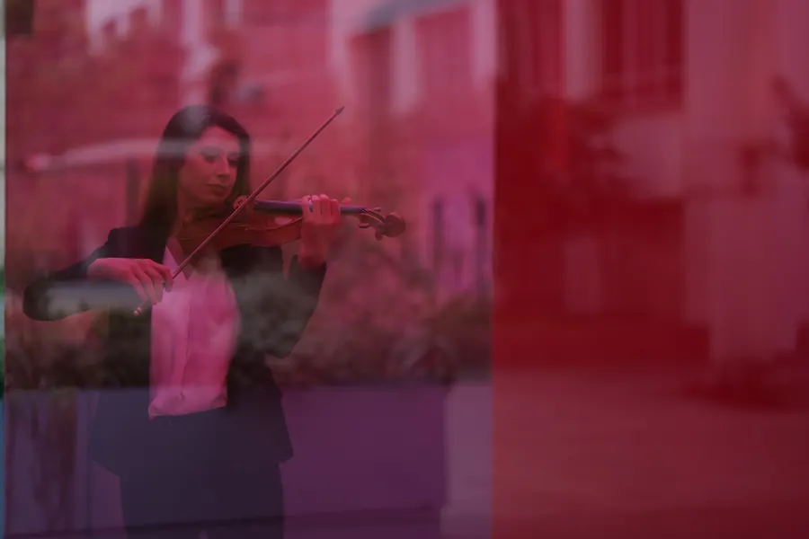 Madalyn playing violin, seen through the red glass of Bill and Coo in Downtown Los Angeles