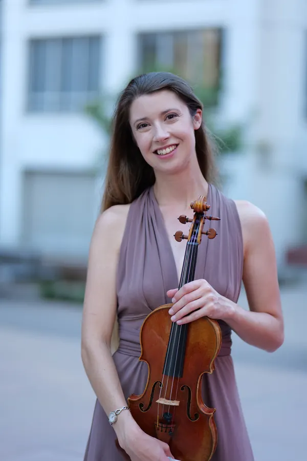 Madalyn Parnas Möller holding her violin at dusk, wearing a mauve gown